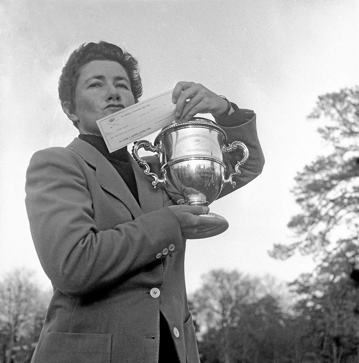 Louise Suggs holds up the winner’s cup and a check for $1,000 after winning the Women’s Titleholders championship in 1959 in Augusta, Ga.