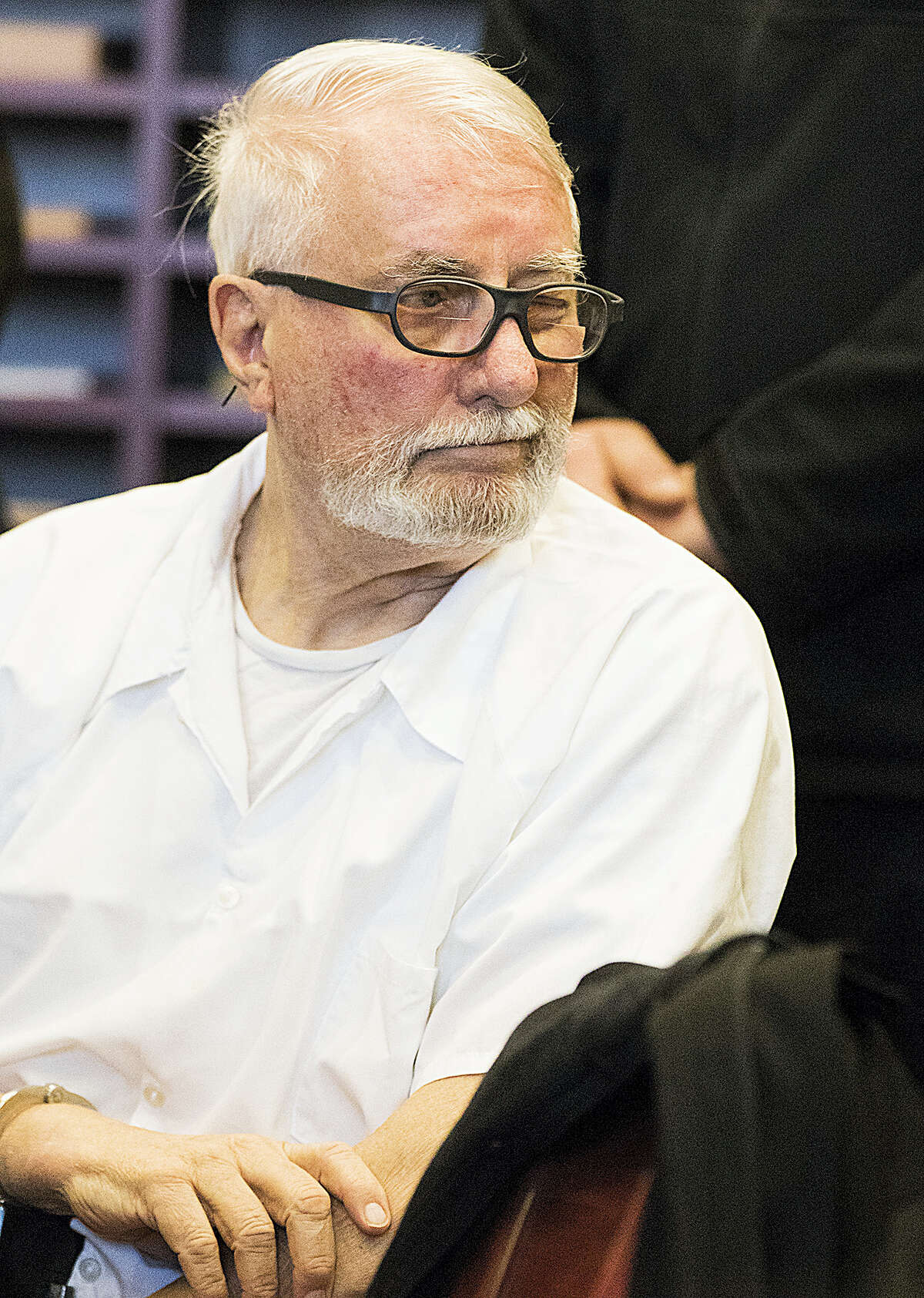 Jack McCullough winks at his stepdaughter Janey O’Connor behind him as he sits during a hearing in the DeKalb County Courthouse on Friday, April 15, 2016 in Sycamore, Ill. McCullough who a prosecutor says was wrongly convicted in the 1957 killing of an Illinois schoolgirl was released Friday shortly after a judge vacated his conviction, meaning that one of the oldest cold cases to be tried in U.S. history has officially gone cold again.