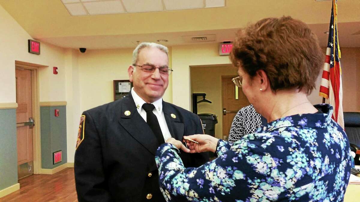 Fire Marshal Ed Bascetta is pinned by his wife at the Board of Public Safety meeting in Torrington Wednesday.