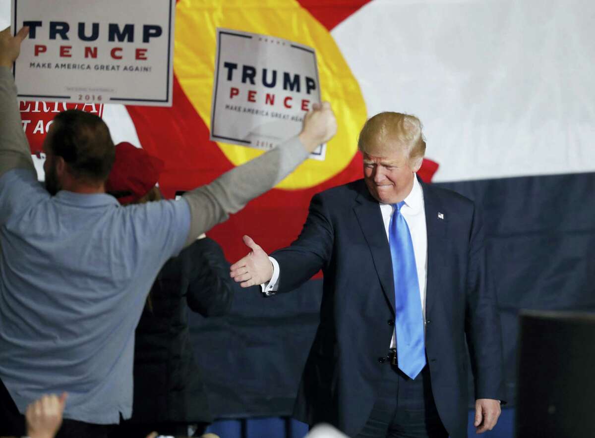 Republican presidential candidate, Donald Trump ,reaches out to shake hands with a supporter while taking the stage at a campaign rally late on Nov. 5, 201 in Denver.