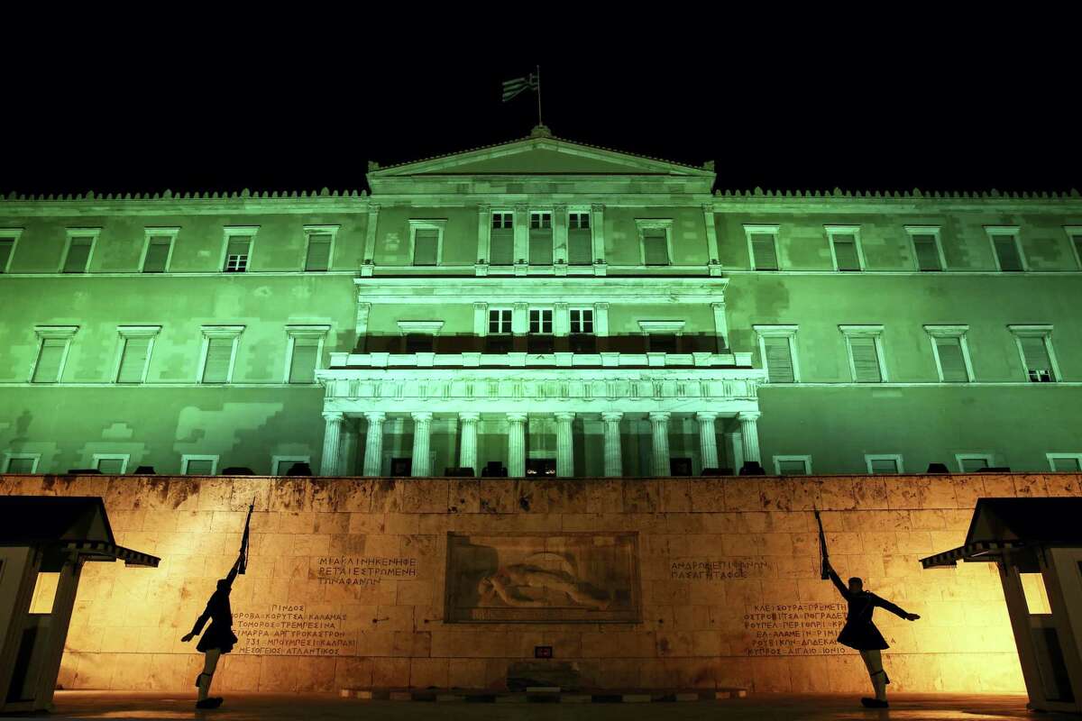Presidential guards perform their ceremonial duties in front of the Greek parliament in Athens on Nov. 5, 2016. The parliament was illuminated in green light to celebrate the entry into the U.N. Paris Climate Change agreement.