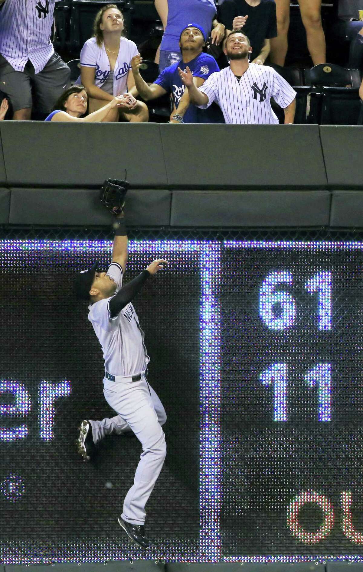 Yankees right fielder Aaron Hicks climbs the outfield wall on Alcides Escobar’s home run in the seventh inning on Monday.