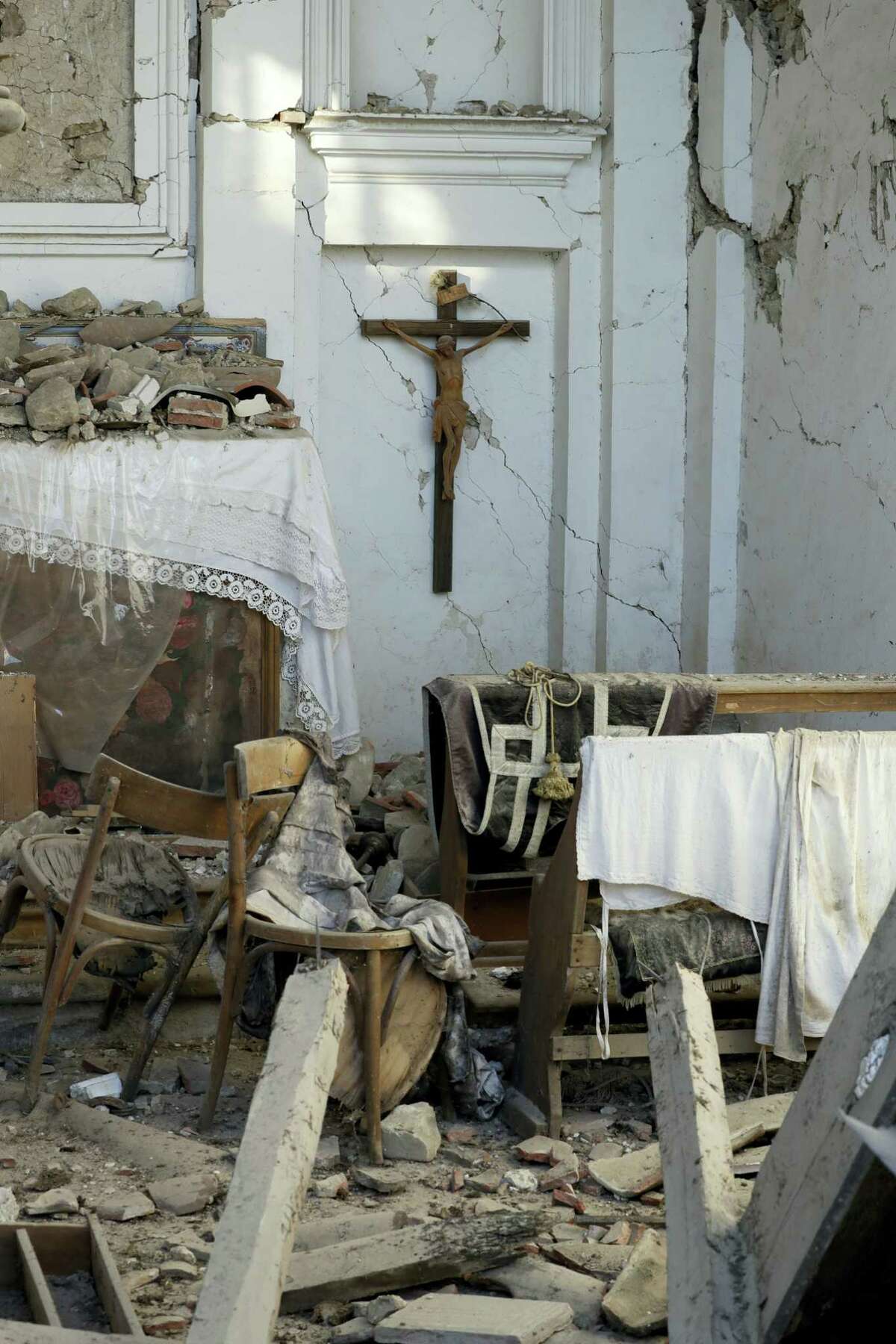 A crucifix hangs on the wall of the severely damaged church in the village of Santi Lorenzo e Flaviano, central Italy, Saturday, Aug. 27, 2016. Italians bid farewell Saturday to victims of the devastating earthquake that struck a mountainous region of central Italy this week.