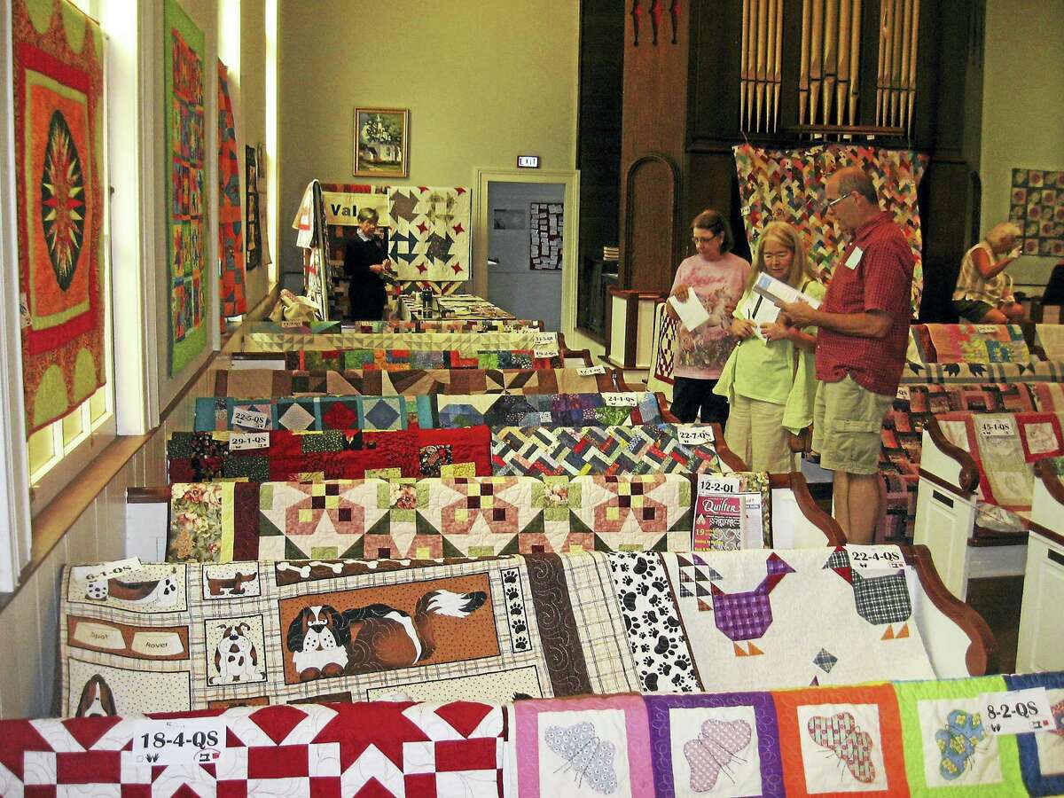 Visitors view quilts draped over church pews.