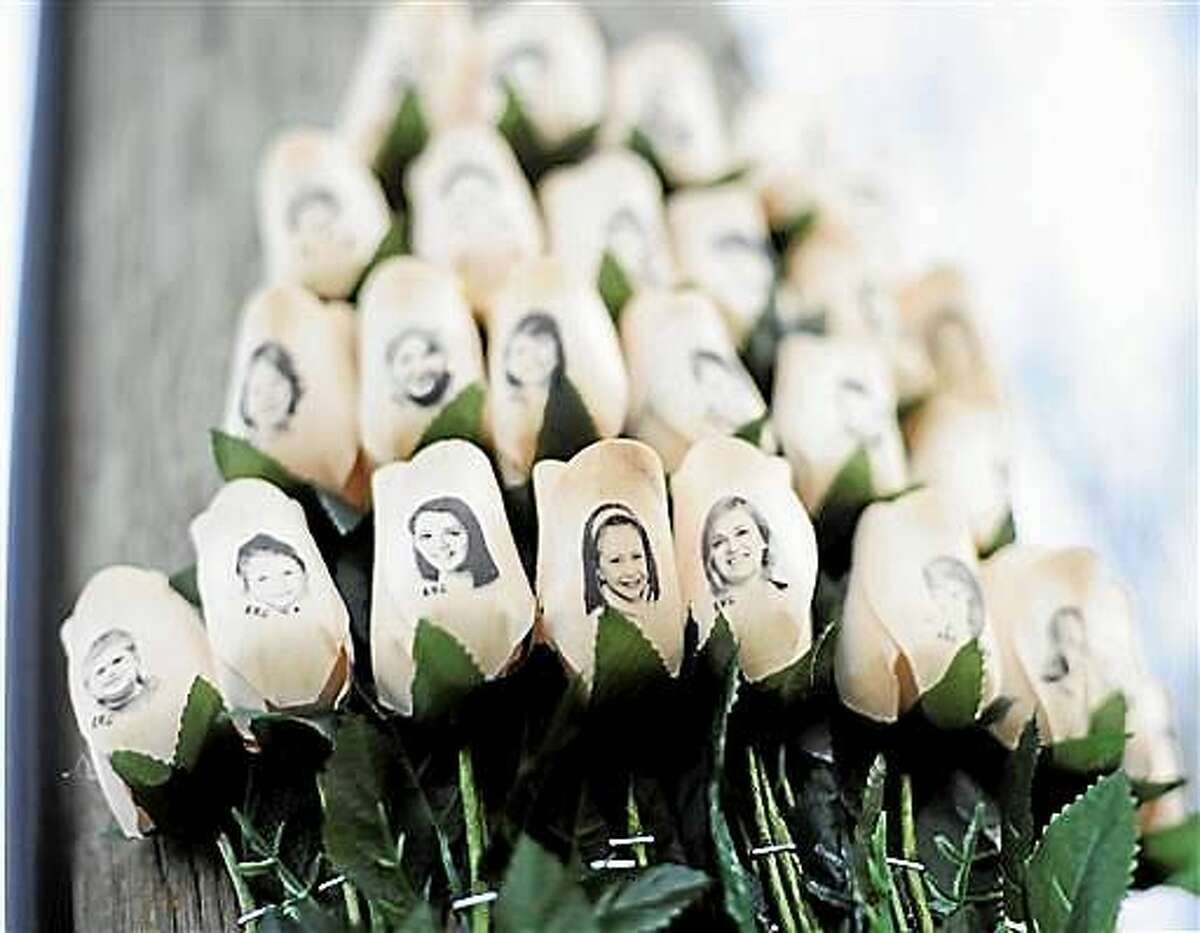 In this Jan. 14, 2013 file photo, white roses with the faces of victims of the Sandy Hook Elementary School shooting are attached to a telephone pole near the school on the one-month anniversary of the shooting.
