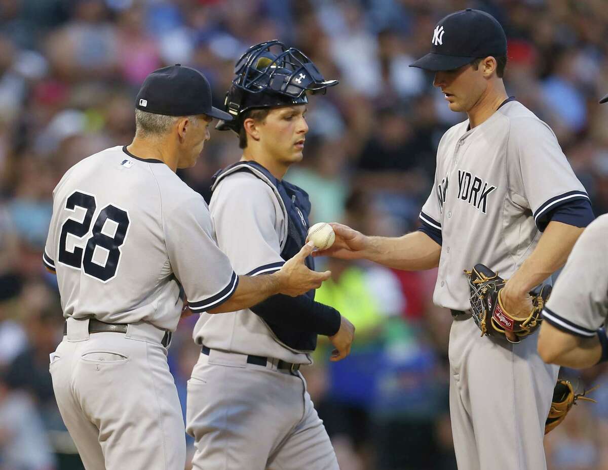 New York Yankees relief pitcher Bryan Mitchell, right, hands the ball to manager Joe Girardi (28) catcher John Ryan Murphy, center, watches in the fifth inning of a baseball game against the Chicago White Sox in Chicago, Saturday, Aug. 1, 2015. (AP Photo/Jeff Haynes)