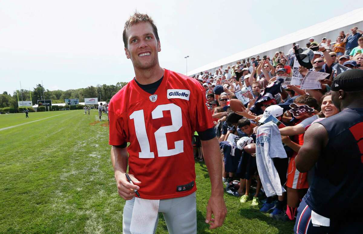 Patriots quarterback Tom Brady walks down the line of fans signing autographs Saturday in Foxborough, Mass.