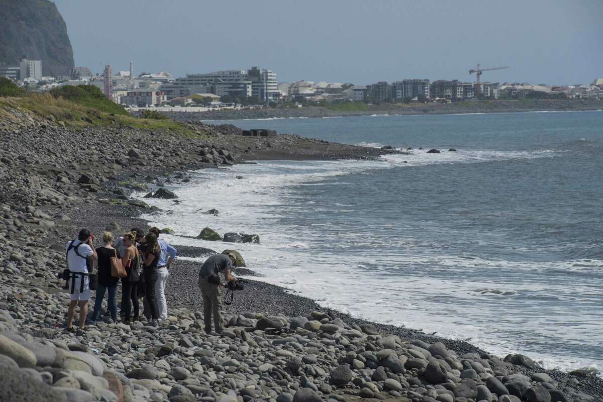 Workers for an association responsible for maintaining paths to Jamaica beach from being overgrown by shrubs, search the beach for possible additional airplane debris near the shore where an airplane wing part was washed up, in the early morning near to Saint-Denis on the north coast of the Indian Ocean island of Reunion on Aug. 2, 2015.