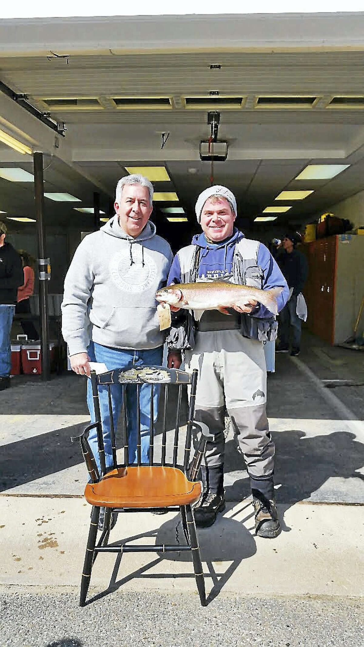 Brandon D’Angelo, 34, of Barkhamsted shows off his 24 ½-inch rainbow trout and his prize, a customized wooden Hitchcock chair, along with his father, Gary D’Angelo, of Winsted at the 67th annual Riverton Fishing Derby on the West branch of the Farmington River near the Old Riverton Inn at 436 E. River Road in Riverton Saturday.