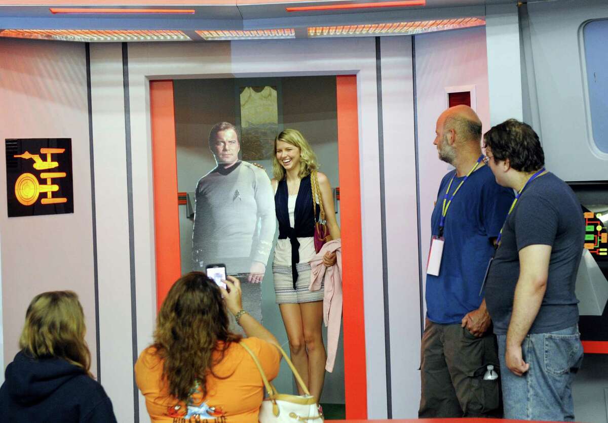 AP Photo/Hans Pennink In this Saturday, Aug. 13, 2016, photo, Kara Benoit of Frederick, Md., poses for a photograph with a cardboard cutout of Capt. James T. Kirk in the turbo lift entrance to the bridge of the replica starship Enterprise during the Trekonderoga festival in Ticonderoga, N.Y. Sets mimicking those of the 1960s TV series “Star Trek” have become a tourist attraction in upstate New York.