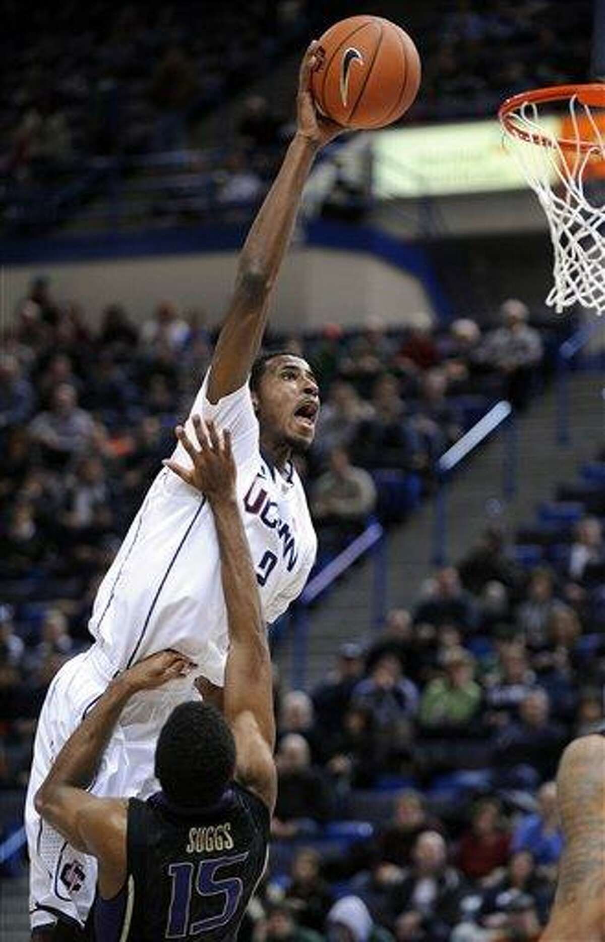 Connecticut's DeAndre Daniels, left, drives over Washington's Scott Suggs during the first half of an NCAA college basketball game in Hartford, Conn., Saturday, Dec. 29, 2012. (AP Photo/Fred Beckham)