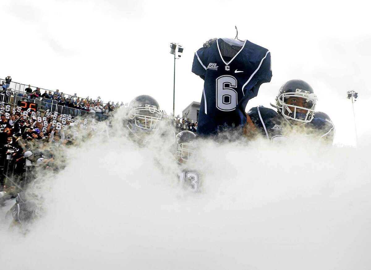 Kashif Moore carries the jersey of Jasper Howard onto the field before UConn’s game against Rutgers on Oct. 31, 2009, at Rentschler Field in East Hartford.