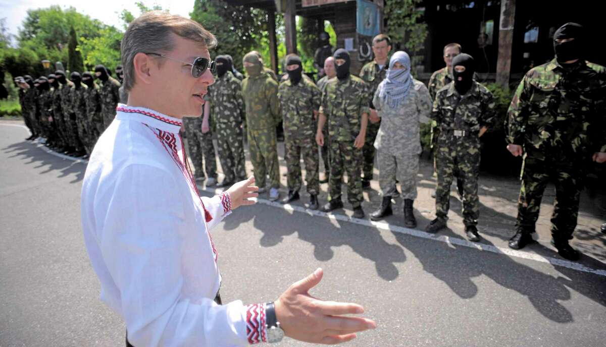Oleh Lyashko, left, leader of Ukrainian Radical Party and presidential candidate, speaks to self defense volunteers at a training ground outside Kiev, Ukraine, Friday, May 23, 2014. Ukraine is holding a presidential election Sunday but it has become downright dangerous for many in the east to be associated with the vote, since the eastern regions of Donetsk and Luhansk declared independence last week. Ukrainian police and election officials accuse pro-Russia gunmen there of seizing election commission offices and threatening members in an effort to derail the presidential vote. (AP Photo/Osman Karimov)