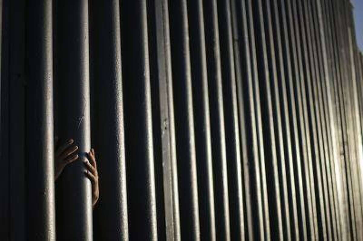 AP10ThingsToSee - Daniel Zambrano, of Tijuana, Mexico, holds one of the bars that make up the border wall separating the U.S. and Mexico where the border meets the Pacific Ocean, Thursday, June 13, 2013 in San Diego. Illegal immigration into the United States would decrease by only 25 percent under a far-reaching Senate immigration bill, according to an analysis by the Congressional Budget Office that also finds the measure reduces federal deficits by billions. (AP Photo/Gregory Bull, File)