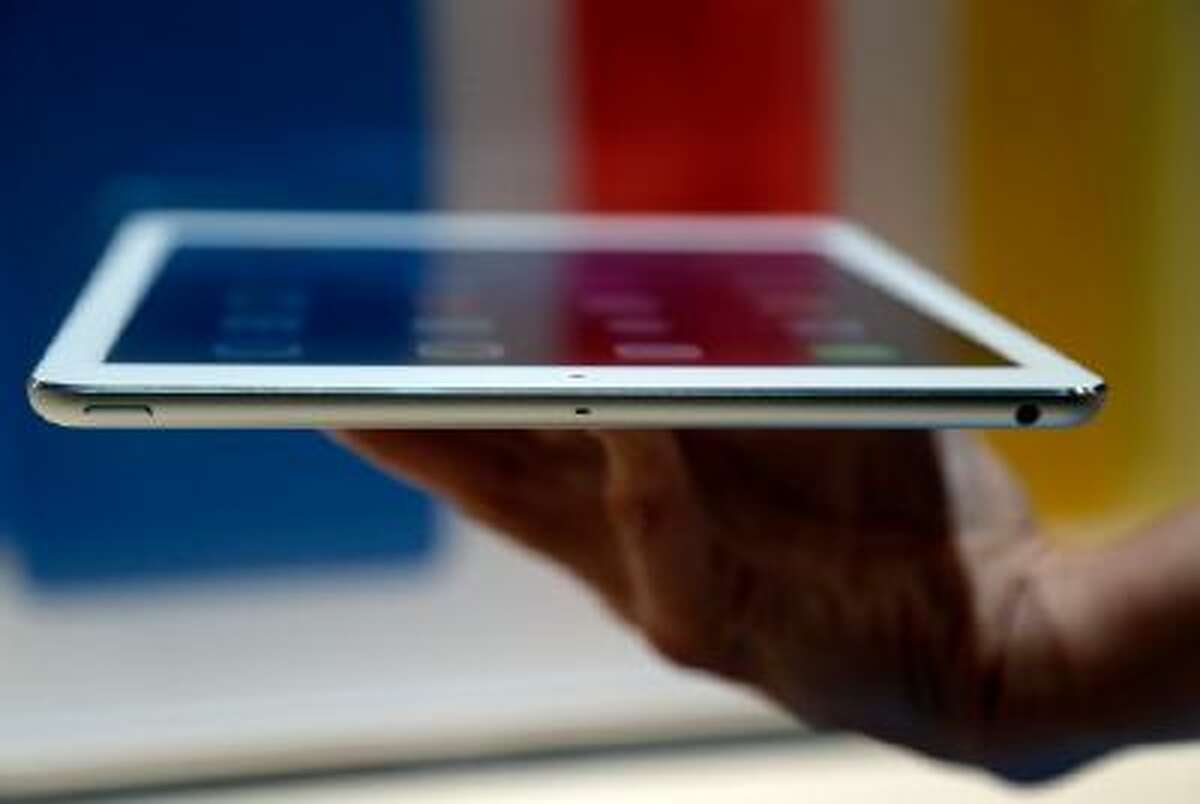 An Apple employee holds up the new iPad Air on Tuesday, Oct. 22, 2013, in San Francisco. The iPad Air weighs just 1 pound, compared with 1.4 pounds for the previous version.