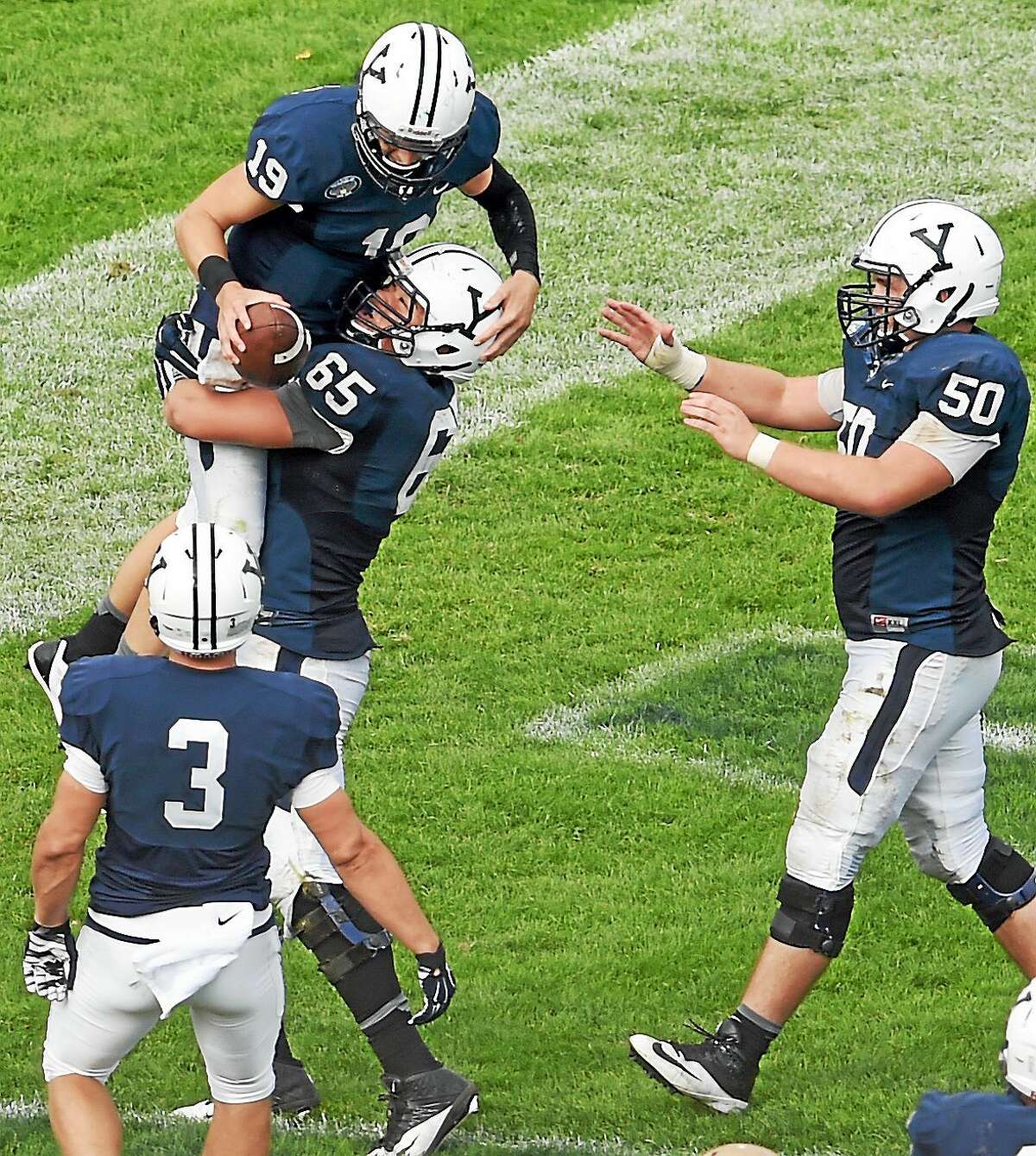 Yale quarterback Morgan Roberts is lifted up in the end zone by teammate Khalid Cannon after Roberts scored a touchdown during the fourth quarter of the Bulldogs’ 54-43 win over Lehigh on Saturday at Yale Bowl.