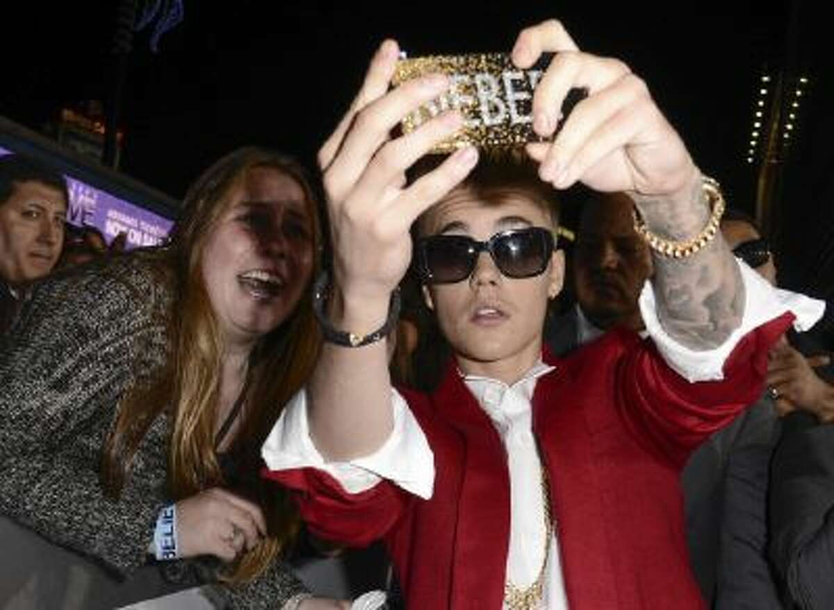 In this Dec. 18, 2013 file photo, singer Justin Bieber takes a selfie with a fan at a premiere in Los Angeles.