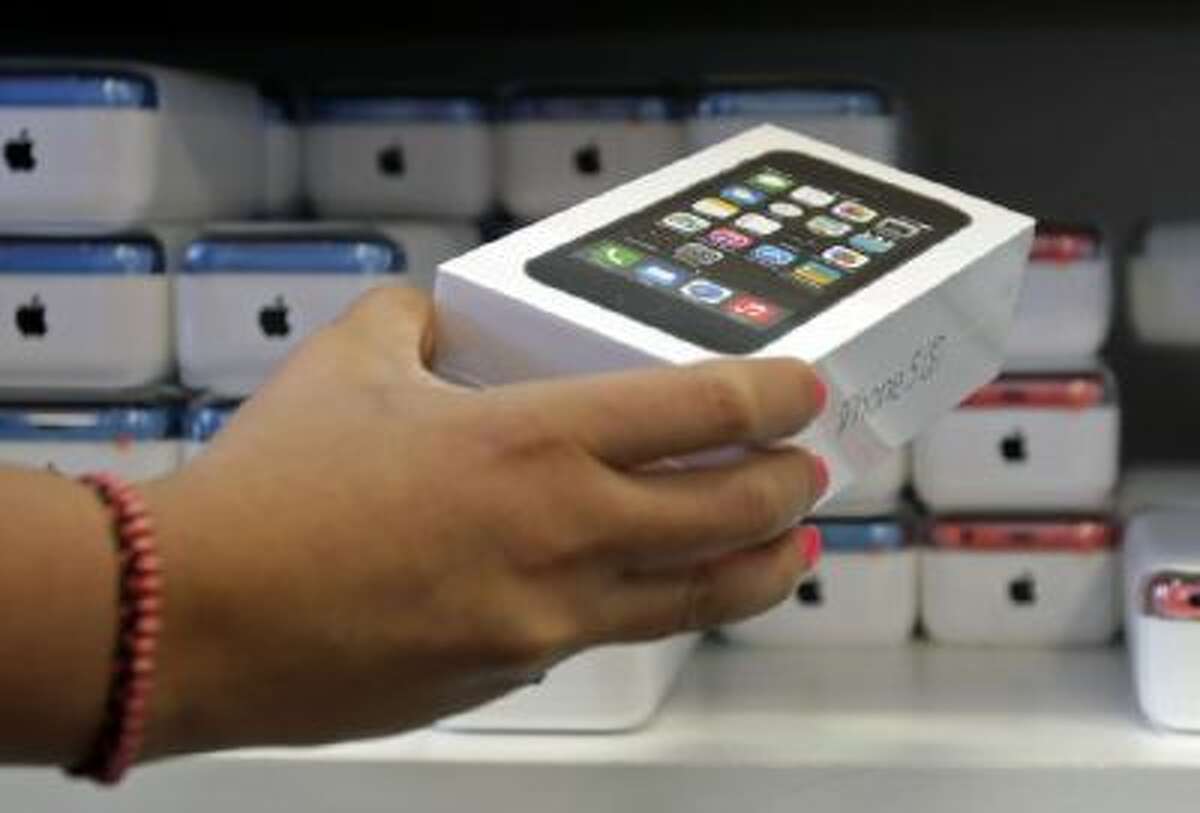 A sales person pulls out an iPhone 5s for a customer during the opening day of sales of the iPhone 5s and iPhone 5C, in Hialeah, Fla., Monday, Sept. 23, 2013.