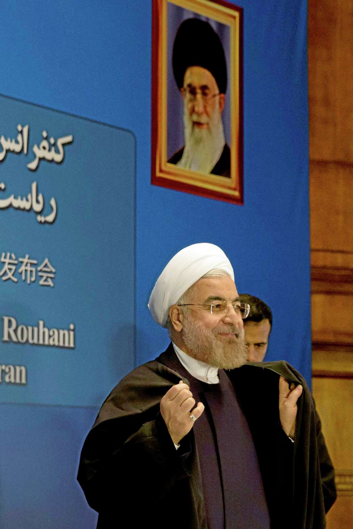 Iranian President Hassan Rouhani prepares to leave after a press conference near a portrait of Iranian Supreme Leader Ayatollah Ali Khamenei at a hotel in Shanghai, China, Thursday, May 22, 2014. Rouhani says an agreement on curbing its nuclear program is "very likely" by July despite a snag in talks last week, but said negotiations might also be extended. (AP Photo/Ng Han Guan)