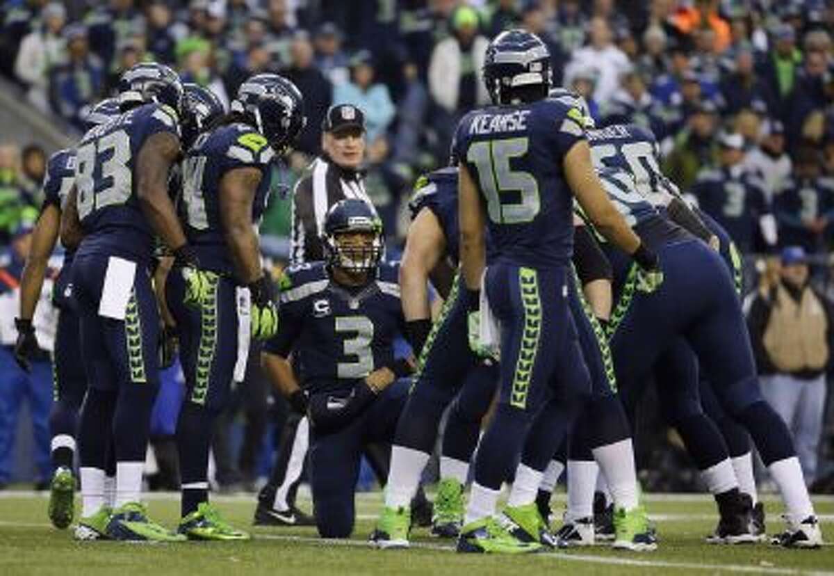 Seattle Seahawks QB Russell Wilson (3) speaks to his teammates, including receivers Ricardo Lockette (83) and Jermaine Kearse (15), during a huddle in the first half of the NFC championship against the San Francisco 49ers in Seattle.