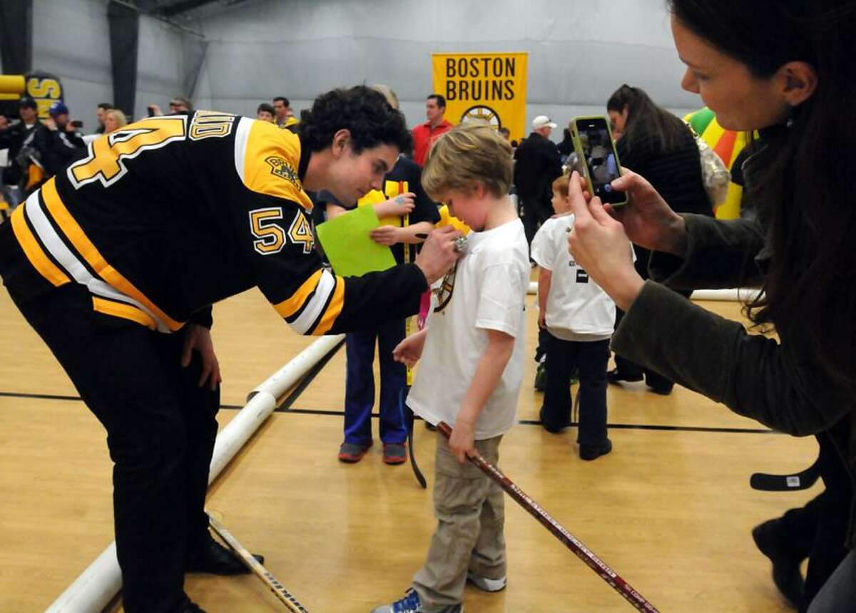 The Boston Bruins made a visit to the Newtown Youth Academy signing autographs and playing street hockey for town residents only. Adam McQuaid signs seven-year-old Logan Johnson's t-shirt while his mom takes a photo. Mara Lavitt/New Haven Register2/18/13