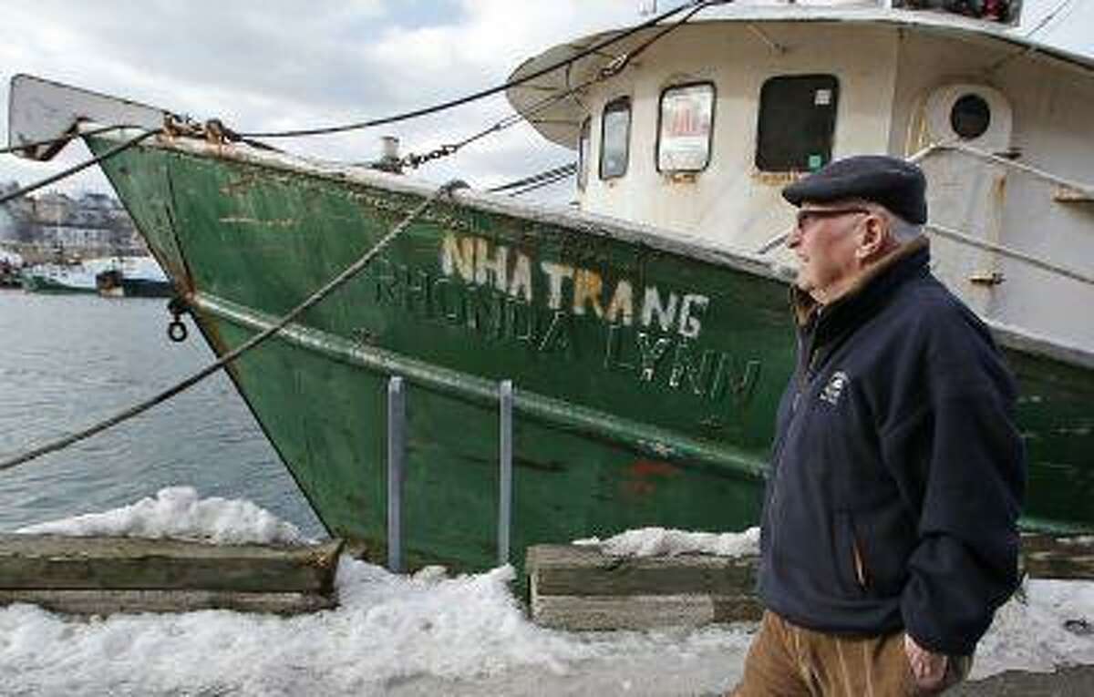 In this photo taken Wednesday, Feb. 13, 2013, Ron Gilson, a 79-year-old life Gloucester native, walks along the fish pier in Gloucester, Mass. In Gilson's life he's worked throughout the fishing industry from working on the wharf in his youth to a historian on Gloucester in his later life. In May, a massive reduction is coming to the catch limit for cod caught in the Gulf of Maine, just outside Gloucester Harbor, and the cuts are acknowledged by fishermen, regulators and environmentalists to be devastating, and perhaps fatal, for the historic industry. (AP Photo/Charles Krupa)
