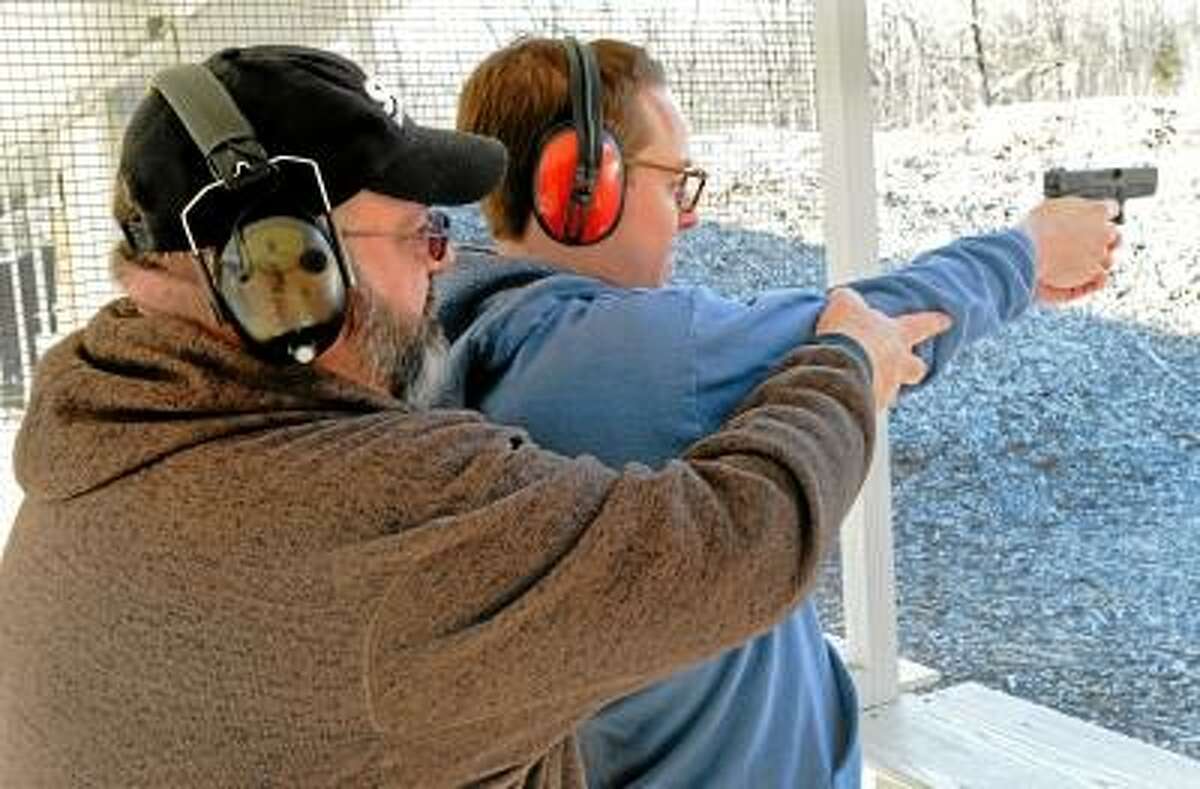 Michael Bellmore, New Haven Register reporter, gets instruction from certified NRA Instructor Michael Peart of Meriden while shooting a Glock 19 9mm semiautomatic pistol during the shooting portion of his NRA Basic Pistol Safety Course. Bellmore is getting a Connecticut Pistol Permit. Thursday, February 7, 2013. Photo by Peter Hvizdak / New Haven Register