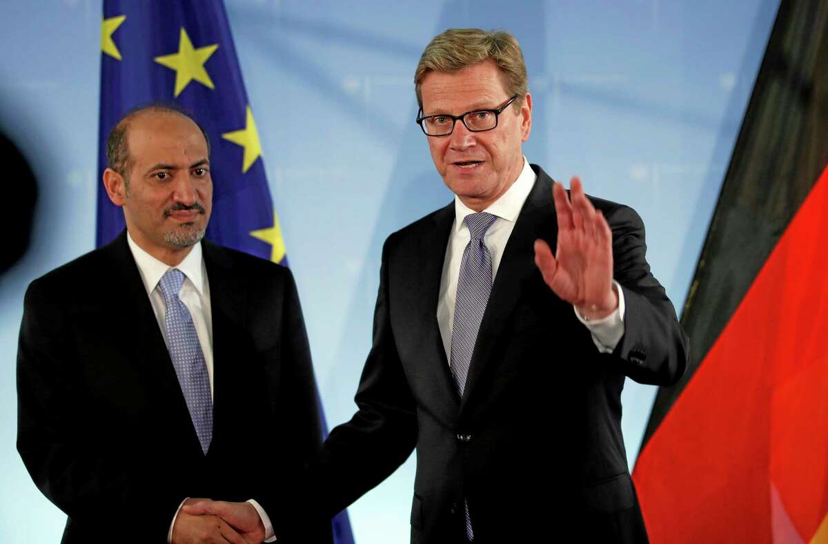 FILE - In this Sept. 2, 2013 file photo, German Foreign Minister Guido Westerwelle, right, and the chairman of the national coalition of the Syrian opposition, Ahmad Jarba, left, shake hands for the media prior to a meeting at the Foreign Ministry in Berlin, Germany. The main Western-backed Syrian opposition group is facing intense pressure from the United States and its European allies to attend a long-delayed peace conference aimed at ending Syria’s civil war, a move that holds the potential to cause an irreparable split in the opposition in exile. (AP Photo/Michael Sohn, File)