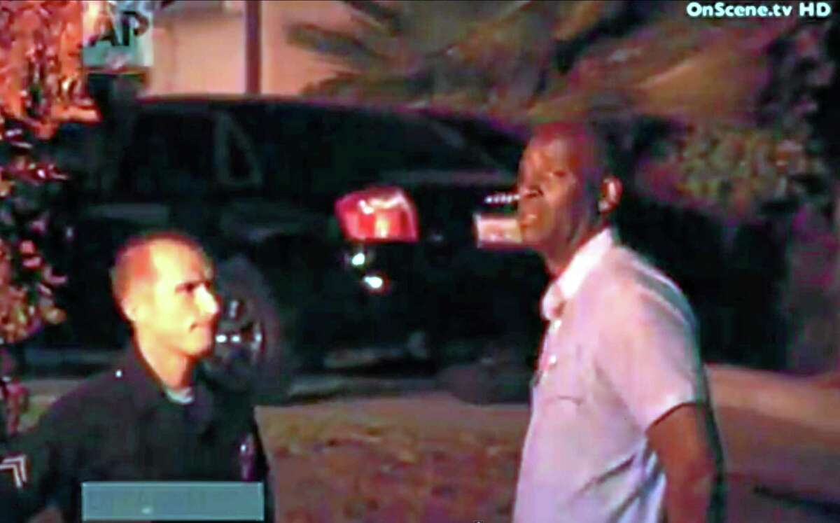In this image taken from video from OnScene.tv, actor Michael Jace, right, is detained by police outside his home in Los Angeles on Monday night, May 19, 2014. Jace, who played a police officer on the hit TV show "The Shield," was arrested on suspicion of homicide after his wife was found shot to death in their Los Angeles home, authorities said. (AP Photo/OnScene.tv)