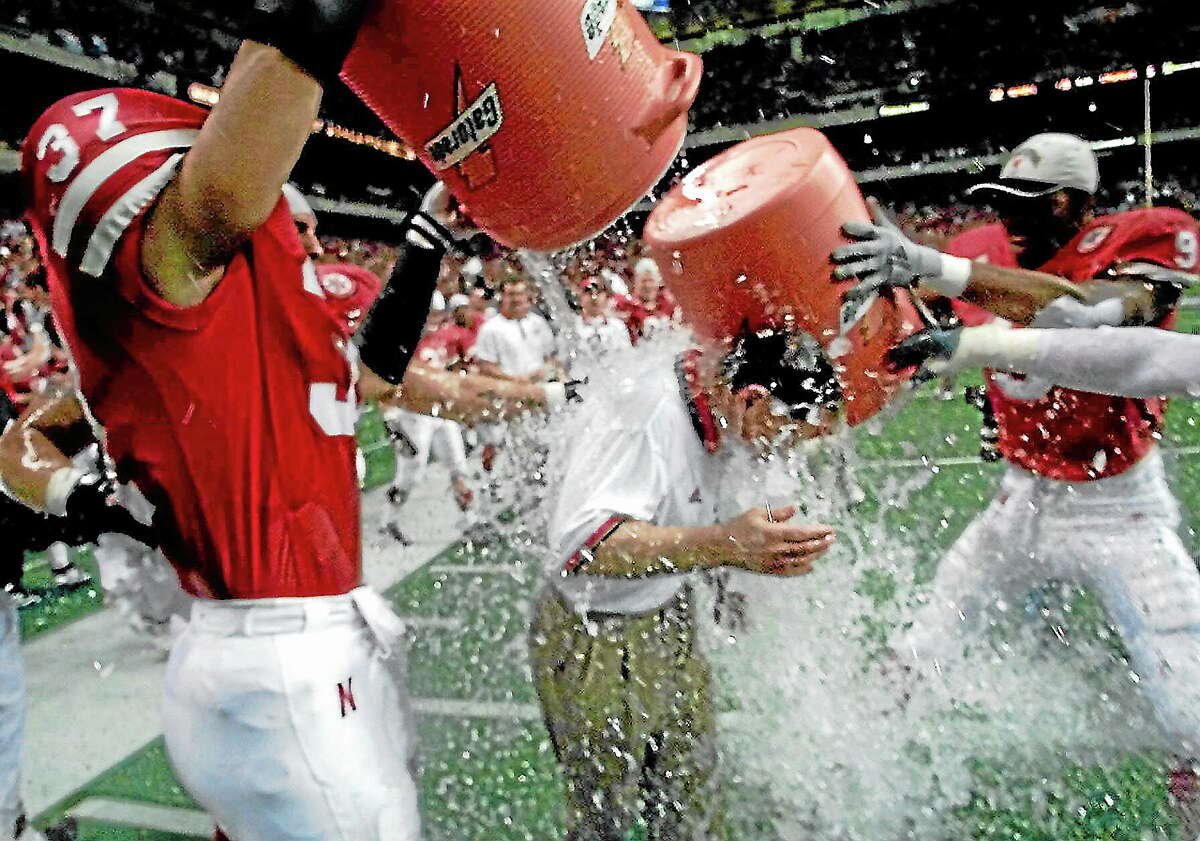 Eric Gay — The Associated Press Nebraska’s Tony Ortiz (37) and Mark Vesral (9) dunk coach Frank Solich with water after the Huskers beat Texas 22-6 in the Big 12 Championship game in Dec. 4, 1999. Ortiz Sr. won two National Championships while playing at Nebraska.