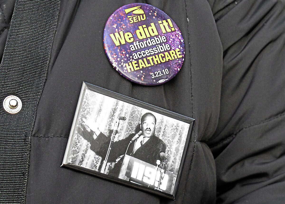 A striking nursing home worker wears buttons on her coat during a rally in Newington, Conn. on Dec. 12, 2012.
