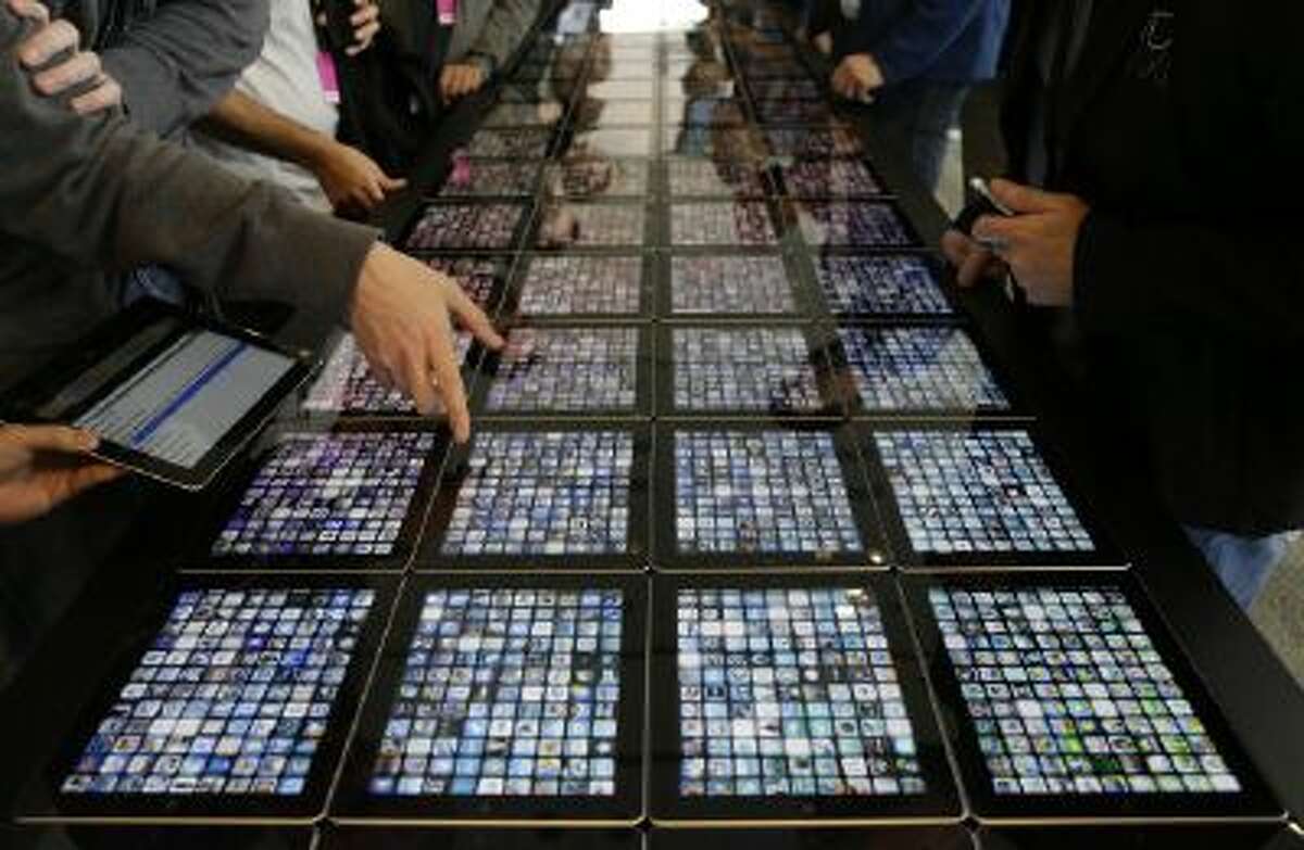 In this Monday, June 10, 2013, file photo, developers look over new apps being displayed on iPads at the Apple Worldwide Developers Conference in San Francisco.