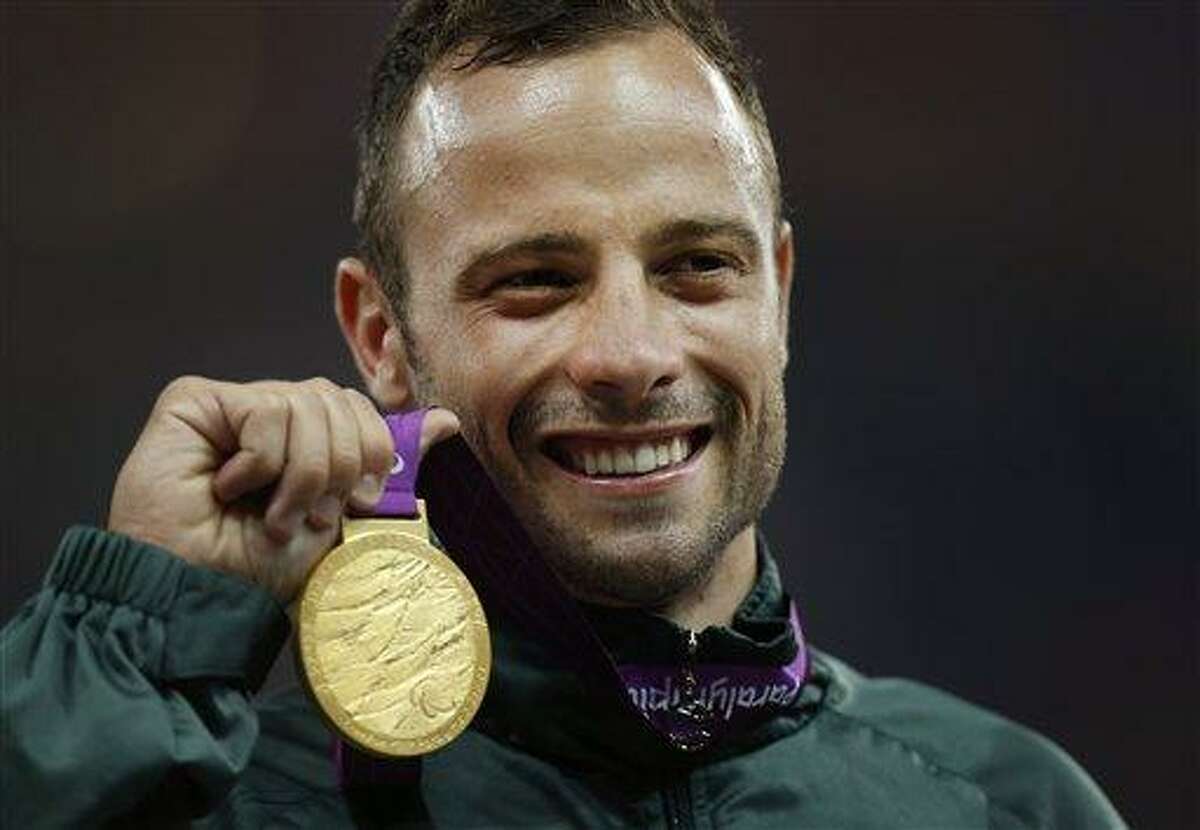 FILE - In this Saturday, Sept. 8, 2012, file photo, Gold medalist South Africa's Oscar Pistorius poses with his medal during the ceremony after winning the men's 400 meters T44 category final during the athletics competition at the 2012 Paralympics, in London. Olympic sprinter Oscar Pistorius has been arrested after a 30-year-old woman was shot dead at his home in South Africa. Police say Pistorius, a double-amputee known as "Blade Runner," was taken into custody after the shooting early Thursday, Feb. 14, 2013, at his home in a gated complex in the country's capital. (AP Photo/Matt Dunham, File)