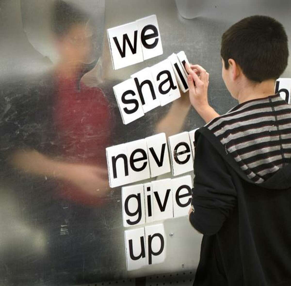 Newtown-Kyle Shelton, 10 of Newtown makes his contribution to the love here now poetry wall at the opening of the Newtown Healing Through The Arts Center. Melanie Styengel/Register