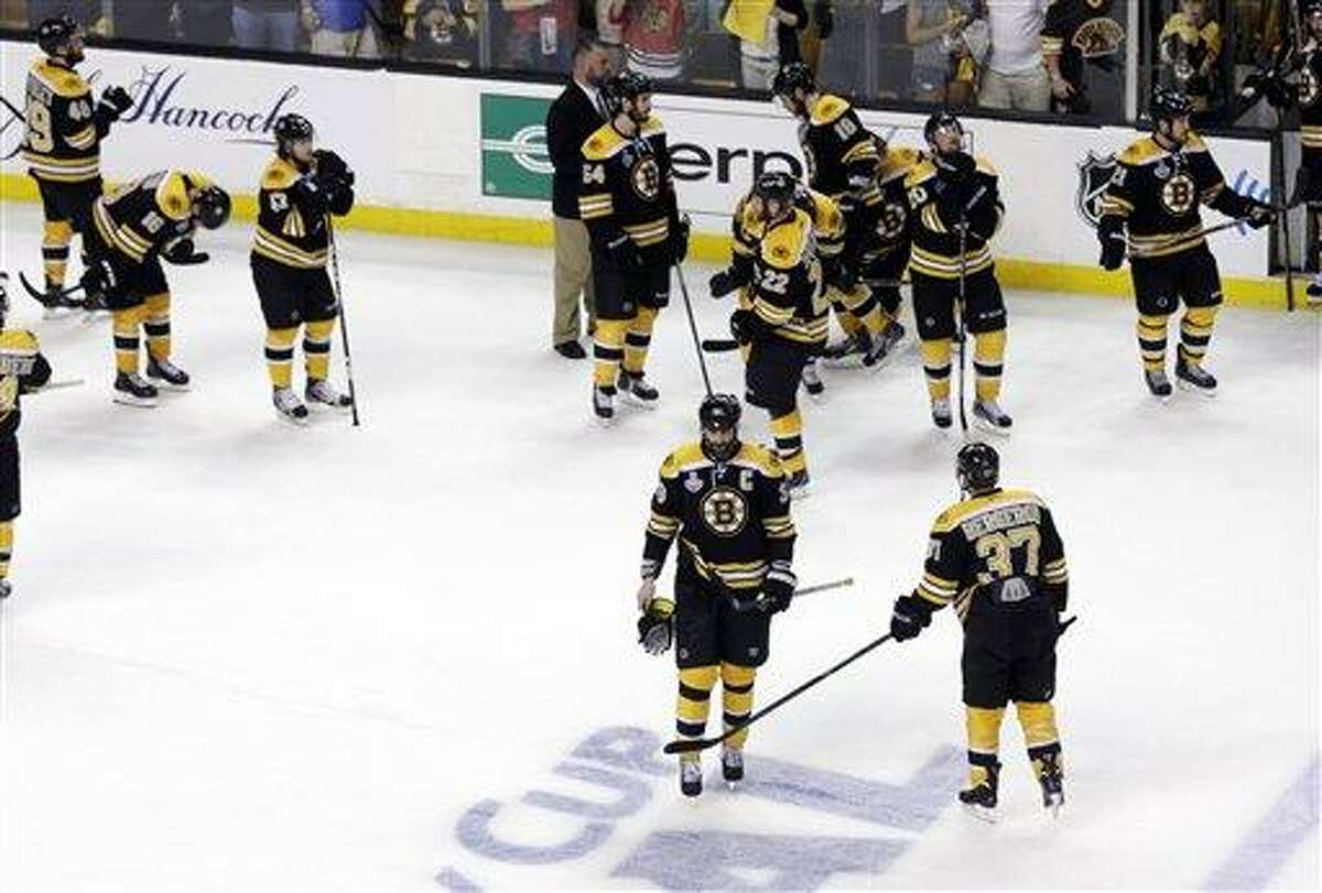 Boston Bruins center Patrice Bergeron (37) taps defenseman Zdeno Chara (33), of Slovakia, as the team stands on the ice while the Chicago Blackhawks celebrate their 3-2 win in Game 6 of the NHL hockey Stanley Cup Finals, Monday, June 24, 2013, in Boston. (AP Photo/Charles Krupa)