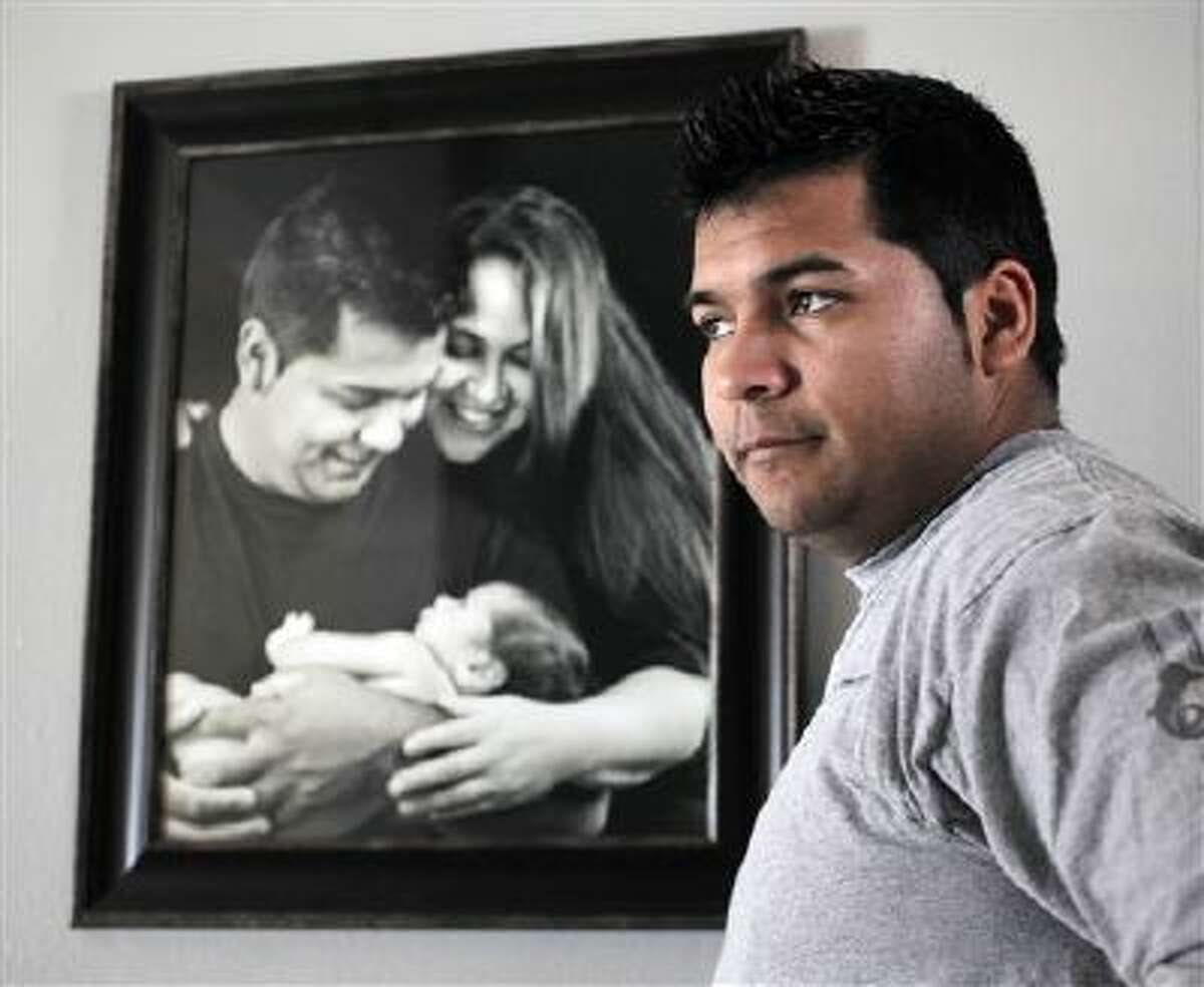 Erick Munoz stands Jan. 3 with an undated copy of a photograph of himself, wife Marlise and their son Mateo, in Haltom City, Texas.