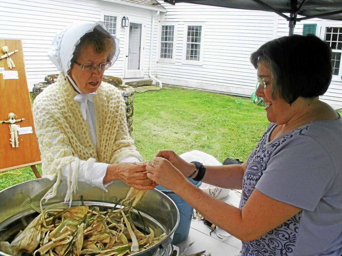 Stephen Underwood/Register Citizen A visitor to Old Barkhamsted Day learns the art of making a corn husk doll.