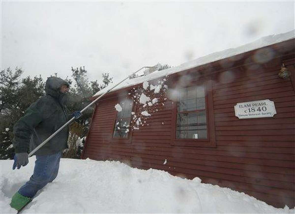 Al Brewer uses a snow rake to clear snow off the roof of his home that dates back to 1840, as rain falls on Monday, Feb. 11, 2013, in Vernon, Conn. (AP Photo /Journal Inquirer, Jim Michaud)
