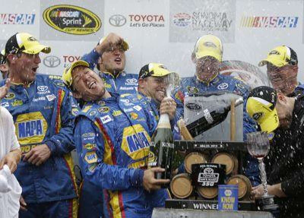 Martin Truex Jr., second from left, sprays his team after winning the NASCAR Sprint Cup series auto race on Sunday, June 23, 2013, in Sonoma, Calif.