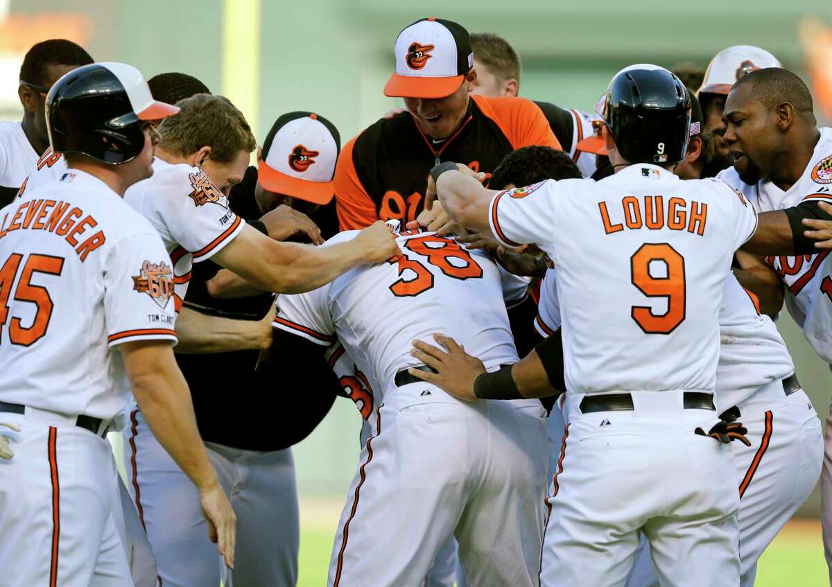 Members of the Orioles celebrate with Jimmy Paredes (38) after he drove in two runs in the 11th inning in the first game of a doubleheader Friday.