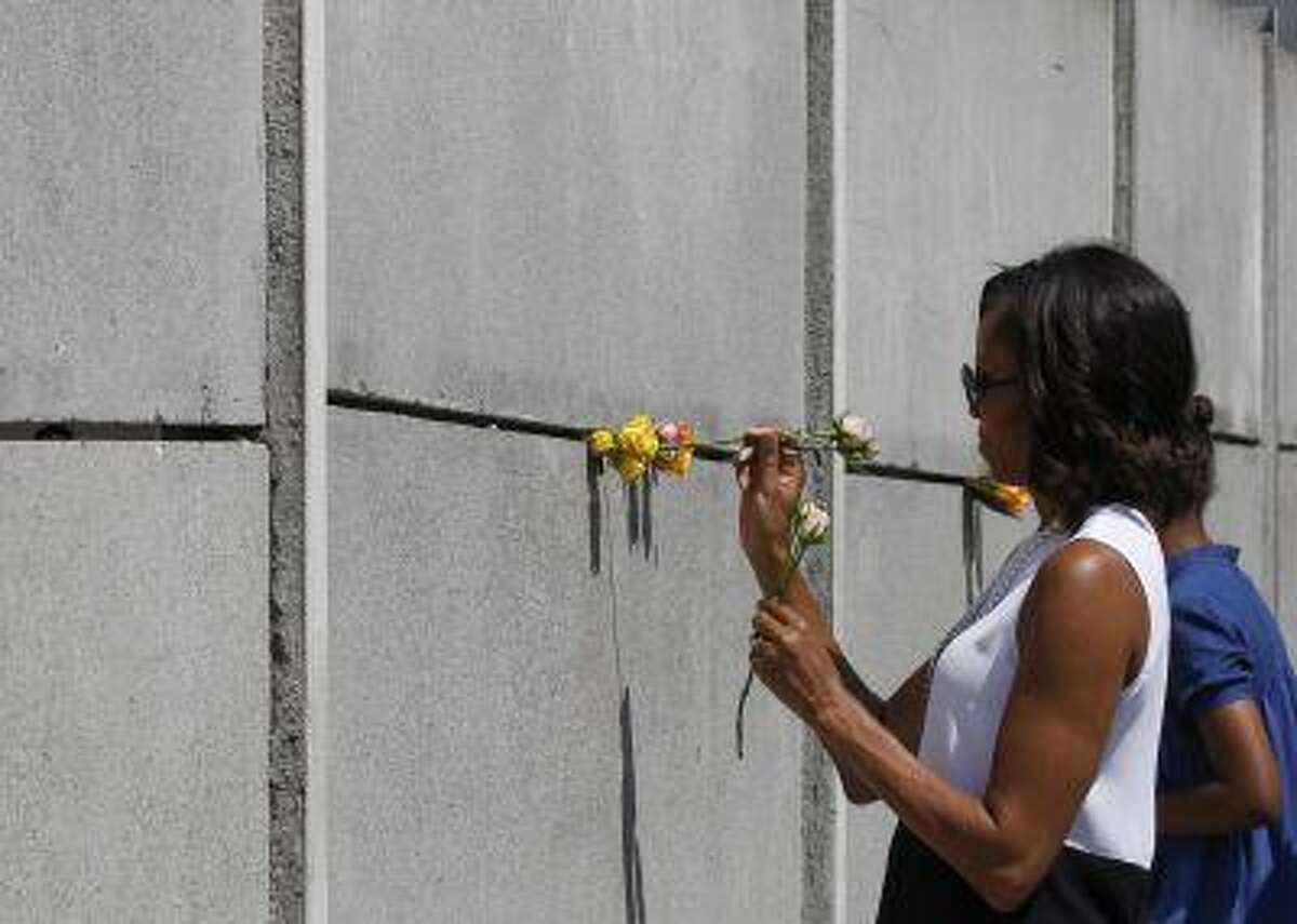 U.S. first lady Michelle Obama and her daughter Sasha place flowers as they visit the Berlin Wall memorial in Bernauer Strasse in Berlin June 19, 2013.