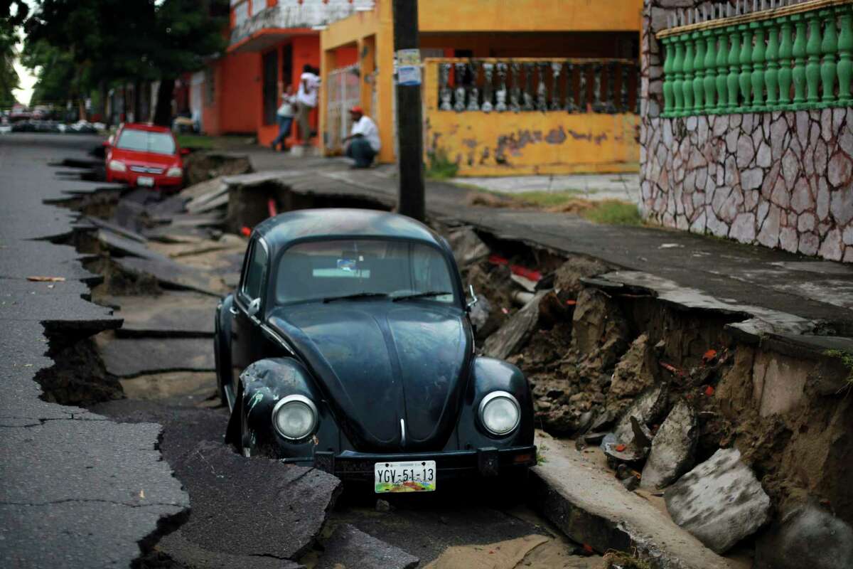 Cars sit on a street that collapsed after heavy rain in the Gulf port city of Veracruz, Mexico, Tuesday, Sept. 2, 2014. The Gulf states of Mexico are bracing for more bad weather as Tropical Storm Dolly crosses the coast and continues moving inland over northeastern Mexico on Wednesday.