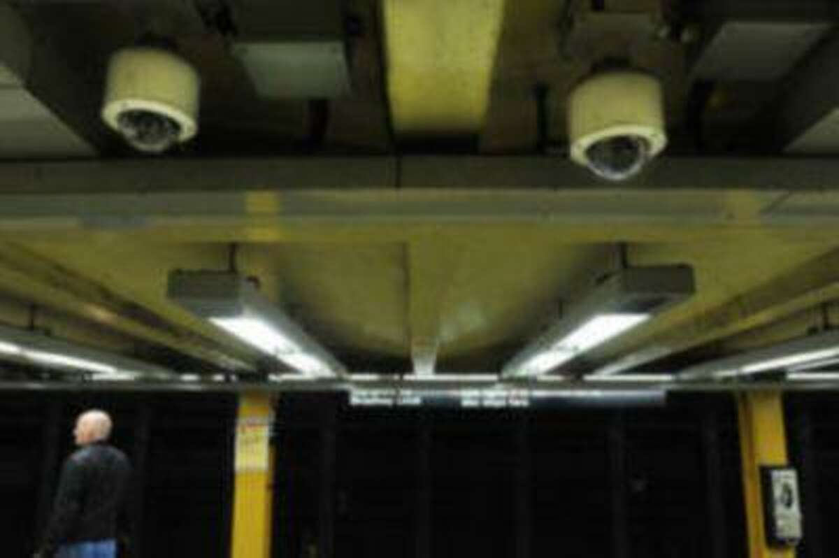 File- In this Tuesday, March 30, 2010, file photo, two ceiling-mounted video surveillance cameras are seen as a man awaits the arrival of a No. 1 subway train at the 34th Street station, in New York. (AP Photo/Stephen Chernin)