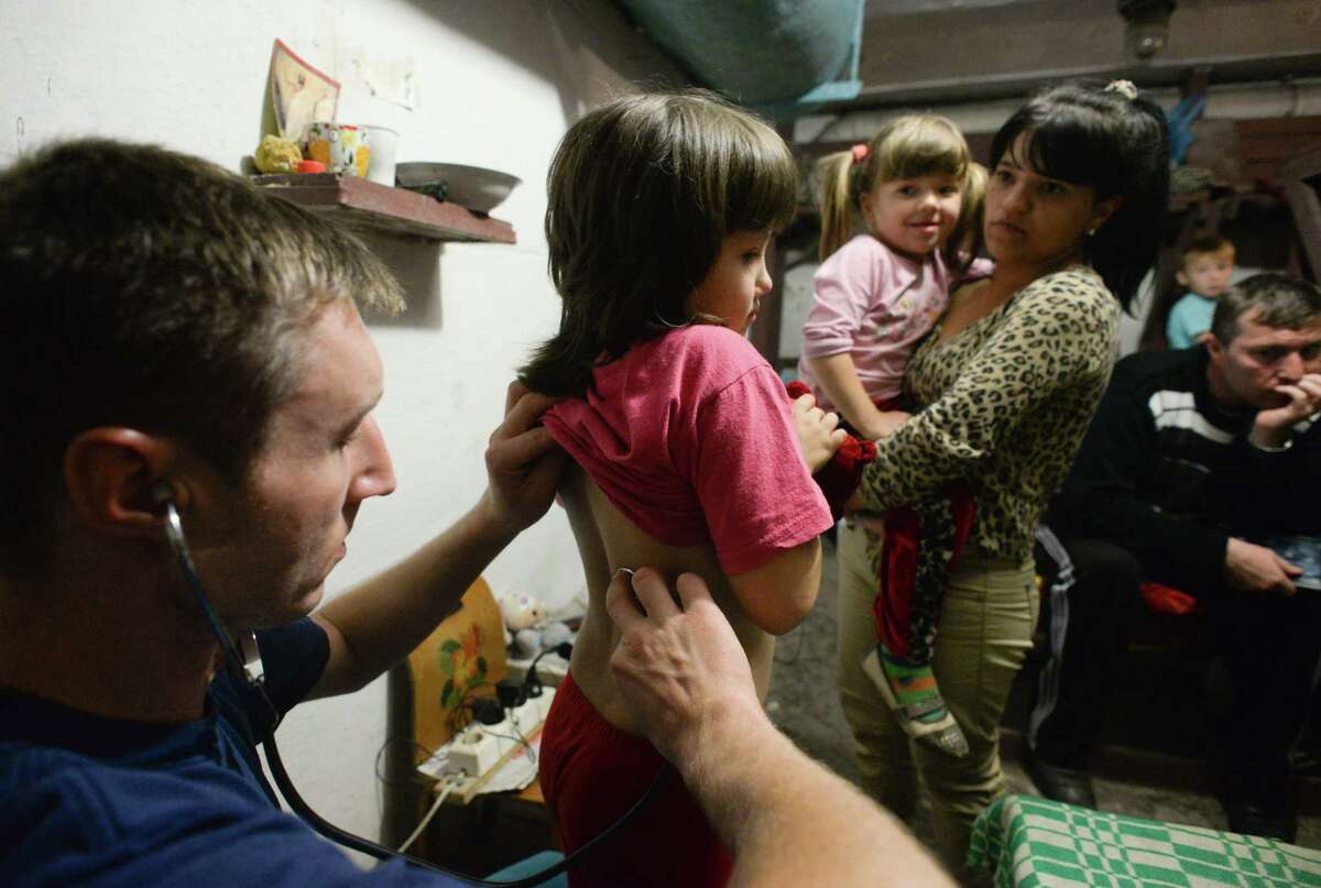 Alexey, volunteer doctor, examines children in bomb shelter in Petrovskiy district in Donetsk, eastern Ukraine, Monday, Sept. 1, 2014. The Petrovskiy district of Donetsk is currently a frontline and one of the districts which suffered the most from the artillery fights between Ukrainian army and Pro-Pussian rebels. (AP Photo/Mstislav Chernov)