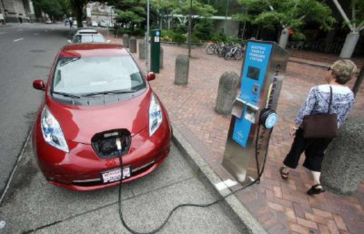 In this Aug. 18, 2011 photo, A Nissan Leaf charges at a electric vehicle charging station in Portland, Ore.