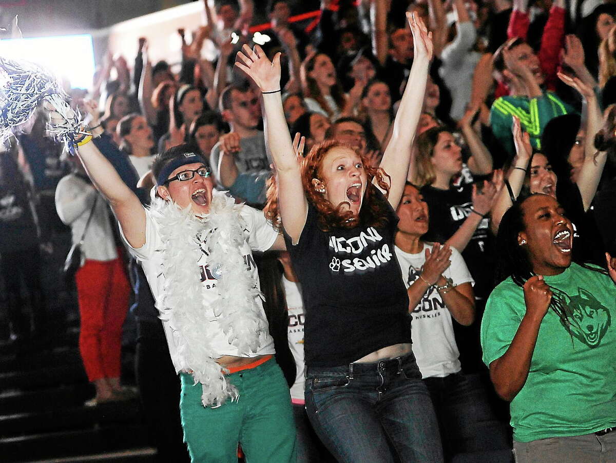 Husein Becirovic of New Britain, Conn., left, Laura Purcell of Stoughton, Mass., center, and Yvonne Ambenge of Mansfield, Conn., right, cheer as they watch the broadcast of the UConn and Notre Dame women’s basketball game for the NCAA title on April 8, 2014, in Storrs, Conn.