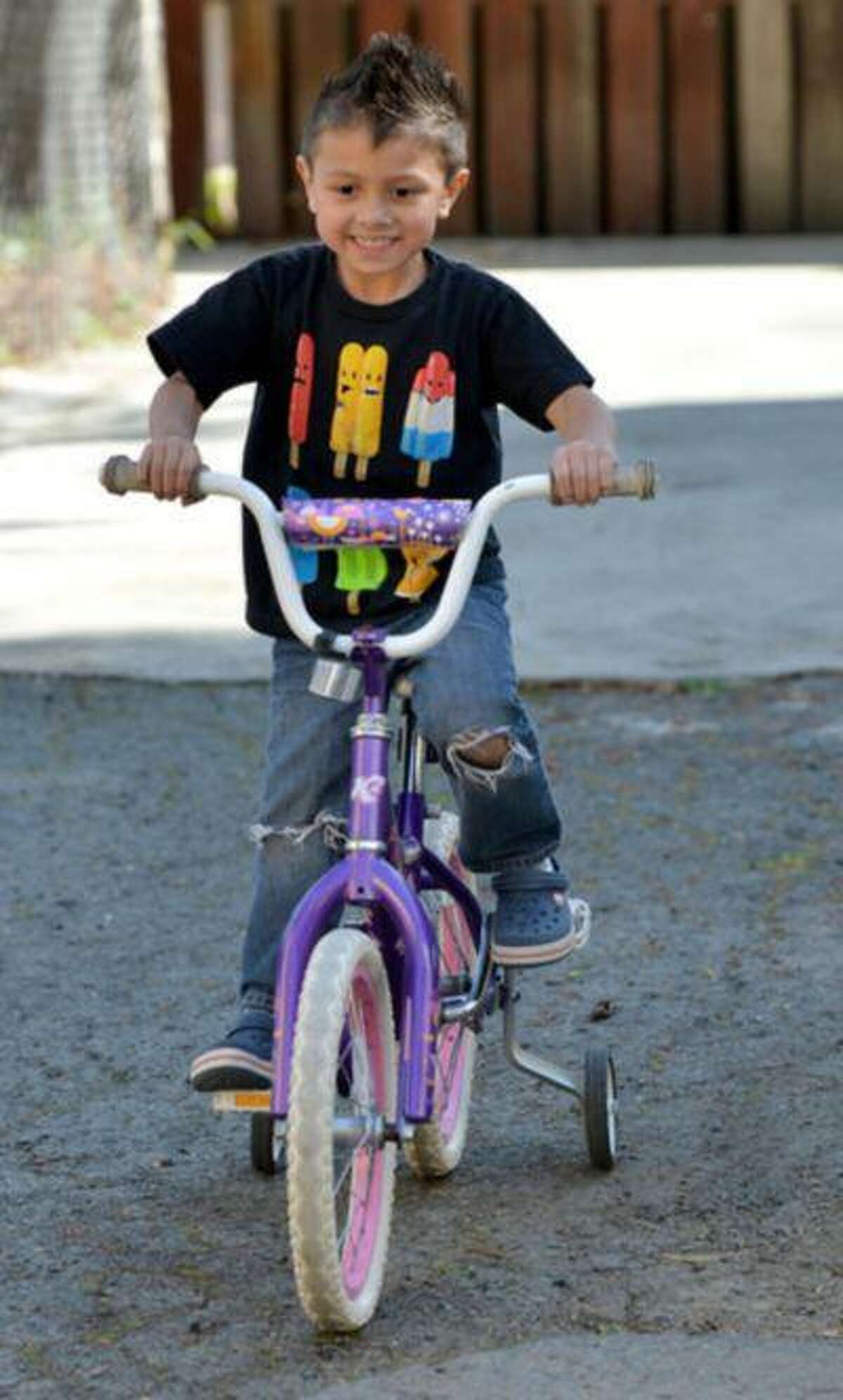 Julian Meija-Blagovic, 4, of Martinez, rides a pink and white bike that his parents bought for him at a garage sale in Martinez, Calif., on Saturday March 23, 2013. His parents, Jorge Meija and Lisa Blagovic, are trying to raise their kids with respect and balance of gender.