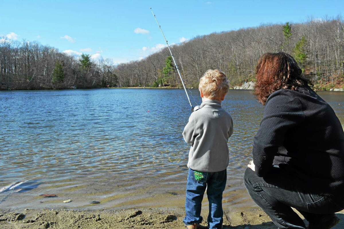 Debbie Alduini helps her 3-year-old son Landon fish in the Elks Lodge's 44th annual children's fishing derby Sunday at Elks Pond in Torrington. This was Landon's first time fishing. John Berry - The Register Citizen