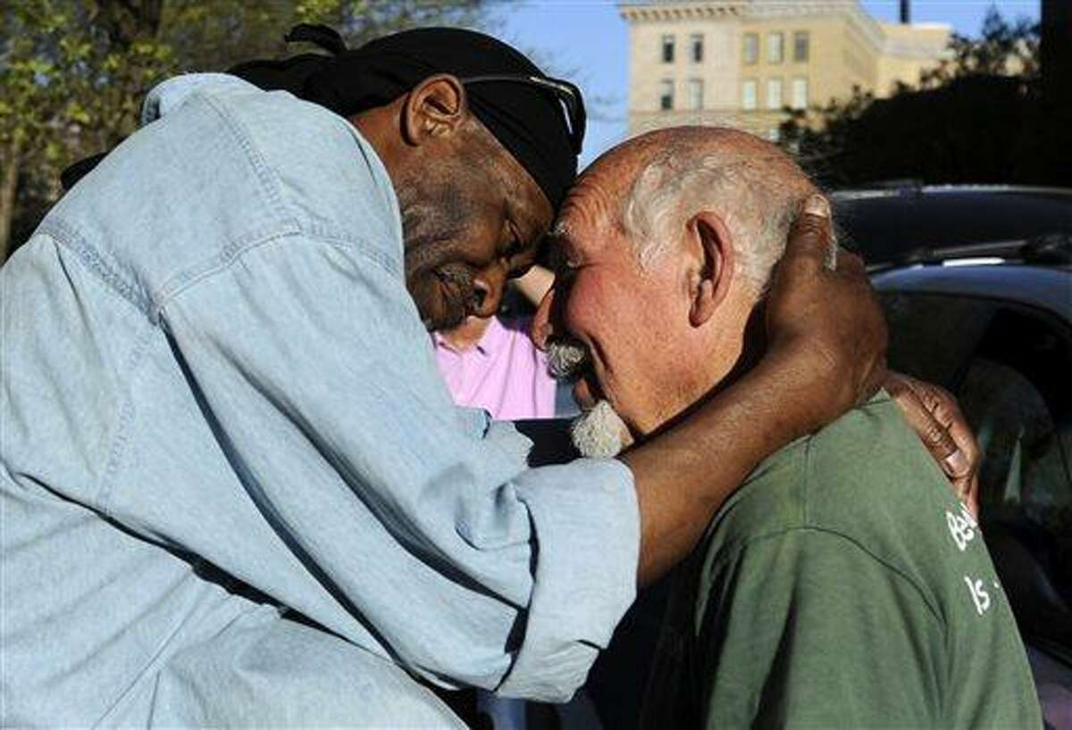 FILE - In this May 1, 2013 file photo, Michael Johnson, left, hugs friend Anthony Cymerys, known as Joe the Barber, in Bushnell Park in Hartford, Conn. For more than 20 years, Cymerys, 82, cut hair alfresco in Hartford for the fee of a hug. On Wednesday, June 13, 2013, Cymerys said as he was setting up, health officials and police told him and his friends, who hand out food to the needy, had to leave because they didn't have permits. (AP Photo/Jessica Hill, File)