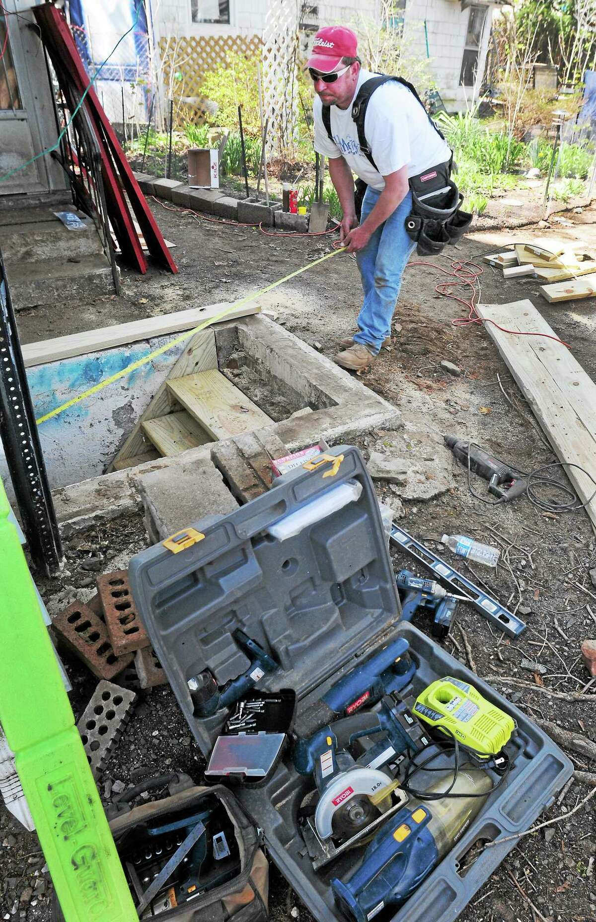 Union carpenter Ricy Bourgoin of Terryville, a HomeFront Inc. volunteer, measures a hatchway that he will repair Saturday at the Malewicki residence on Whitney Avenue in Milford.